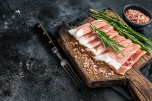 Clube Defumados - Presunto de parma, carne de porco curada seca em uma placa de madeira.